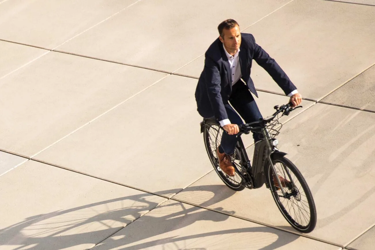 Ein Mitarbeiter im blauen Anzug auf einem E-Bike von Focus auf dem Weg in die Arbeit.